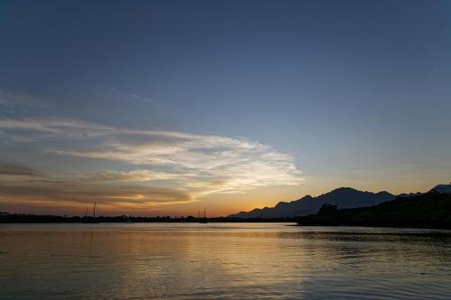 a sunset over a body of water with mountains at Menjangan Ecolodge - CHSE Certified in Banyuwedang