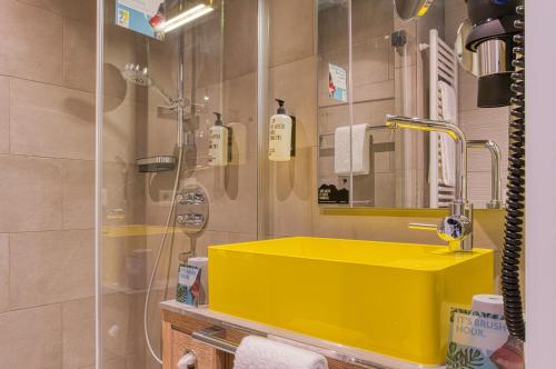 a bathroom with a yellow sink and a shower at NinetyNine Bergedorf in Hamburg