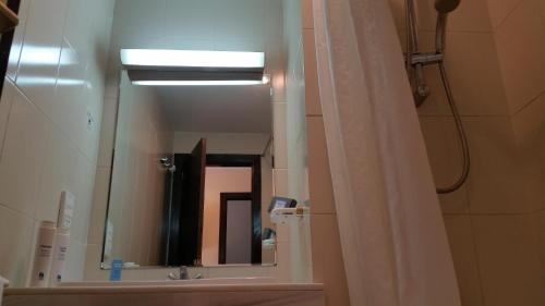 a bathroom with a mirror and a shower curtain at Apartamentos Baños de Ledesma in Salamanca