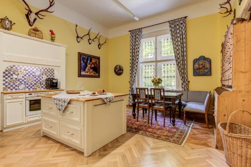 a kitchen with yellow walls and a dining room with a table at Vila Austerlitz in Slavkov u Brna