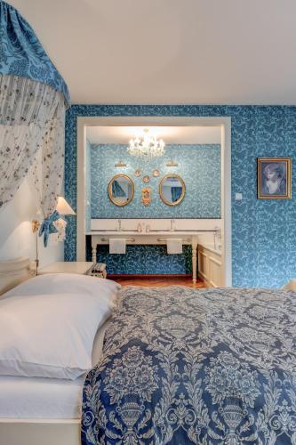 a bedroom with blue walls with a bed and a chandelier at Vila Austerlitz in Slavkov u Brna