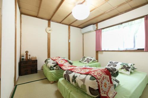 a room with two beds and a window at Kizuna Guesthouse 
