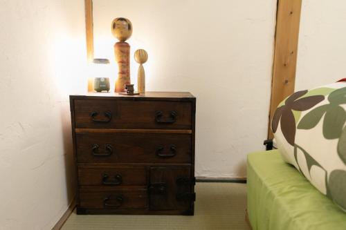 a wooden dresser with a vase on it next to a bed at Kizuna Guesthouse in Kizugawa