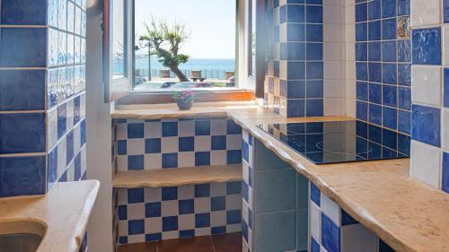 a bathroom with blue and white tiles and a window at Welcomely - Casa Avineira in Alghero