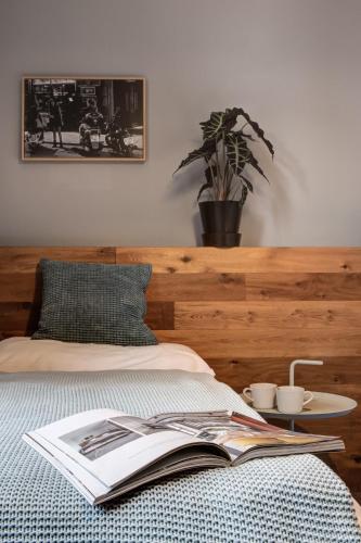 a book on a bed with a plant on a table at Hotel city.city in Ostrava