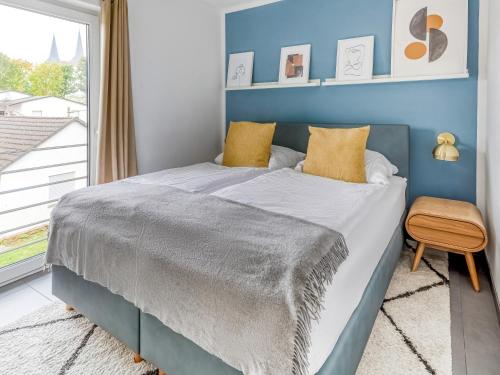 Dormitorio azul con cama y ventana en limehome Montabaur Am Quendelberg, en Montabaur