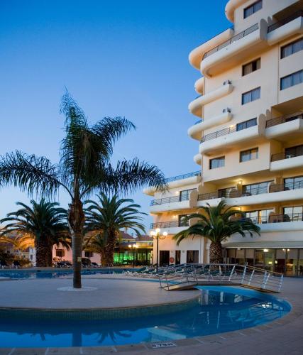 a hotel with palm trees in front of a building at Vila Gale Marina in Vilamoura