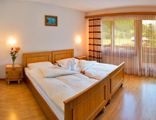 um quarto com uma cama com lençóis brancos e uma janela em Hotel Adler em Saas-Grund