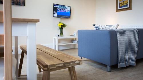 a living room with a blue couch and a wooden table at Brewhouse and Kitchen in Bournemouth
