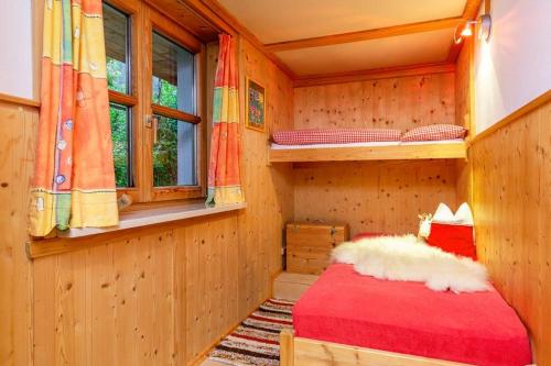 ライト・イム・ヴィンクルにあるWilder Kaiserの木造キャビンの赤いベッド1台が備わるベッドルーム1室です。