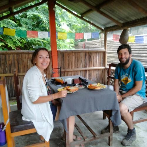a man and a woman sitting at a table with food at Hotel Tiger Tops Sauraha in Sauraha