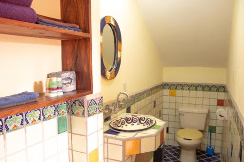 a tiled bathroom with a toilet and a mirror at Hotel Casamar Suites in Puerto Escondido