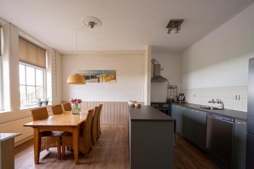 een keuken met een houten tafel en een eetkamer bij Landzicht Vakantiehuis aan de Fluessen in Elahuizen