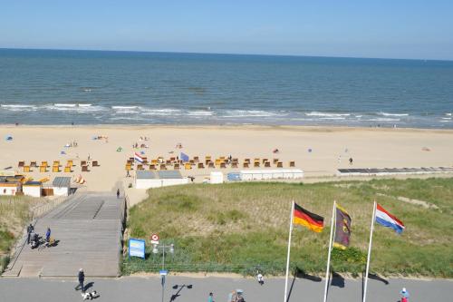 a beach with a boardwalk and a beach with people at Strandhotel Golfzang in Egmond aan Zee