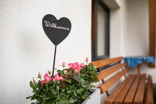 un signo cardíaco en una pared junto a un banco en Bacher Ferienwohnungen, en Virgen