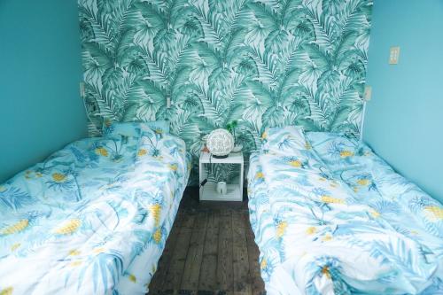 two twin beds in a room with blue walls at ハセノ島　Hotel　Cottage in Kamakura