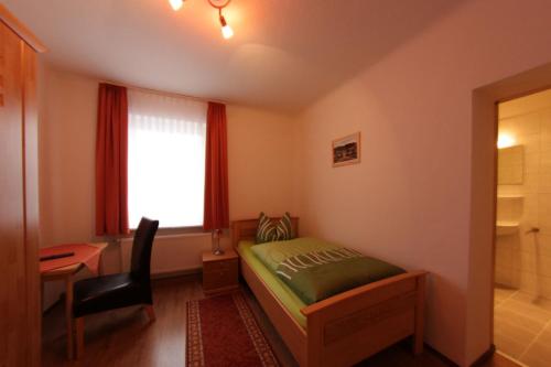 a bedroom with a bed and a desk and a window at Pension Am Ostbahnhof in Gotha