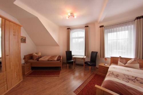 a bedroom with a bed and a couch and two windows at Pension Am Ostbahnhof in Gotha