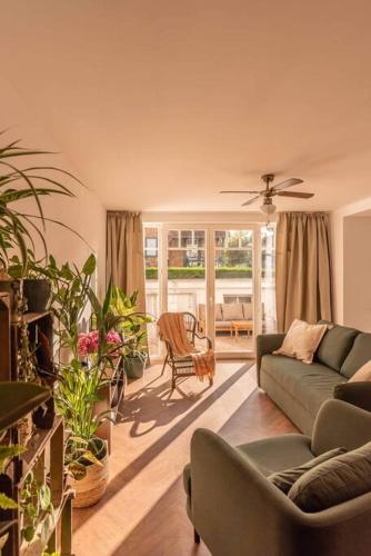 a living room with a couch and some plants at Authentieke vakantiewoning op 200 m van het strand in De Panne