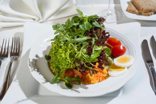 a white plate with a salad and an egg on a table at Loipenstubn in Brixen im Thale