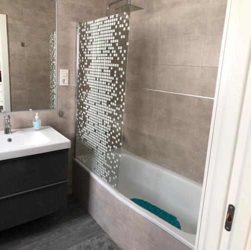 a bathroom with a shower and a tub and a sink at Apartamentos MareaBeach in Torremolinos