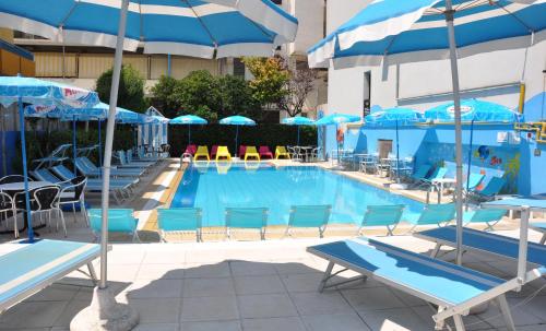a swimming pool with blue chairs and umbrellas at Hotel Adelphi in Riccione