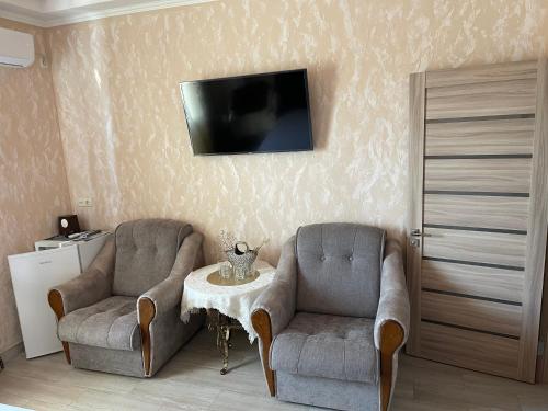 two chairs and a table with a tv on a wall at Hotel Chicago in Umanʼ