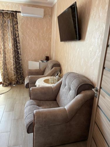 a living room with three couches and a television on the wall at Hotel Chicago in Umanʼ
