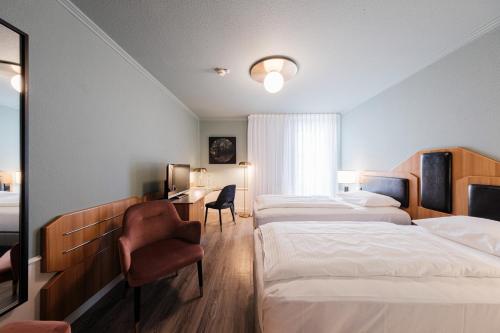 a hotel room with three beds and a chair at Mercure Hotel Pforzheim in Pforzheim