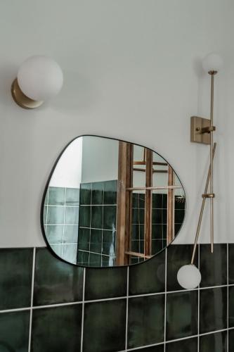 a mirror in a bathroom with green tiles at Rakstvežu apartamenti in Liepāja