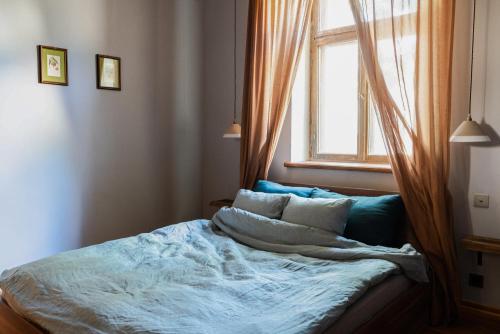 1 cama en un dormitorio con ventana en Rakstvežu apartamenti, en Liepāja