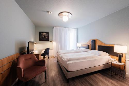 a bedroom with a bed and a chair and a desk at Mercure Hotel Pforzheim in Pforzheim