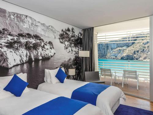 una camera d'albergo con due letti e un dipinto sul muro di Mercure Quemado Al-Hoceima Resort ad Al-Ḥoseyma