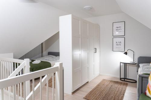 a white bedroom with a bed and a staircase at New Åkrahamn coast house in Sæveland