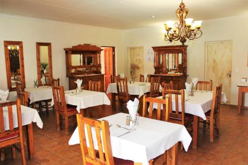a restaurant with white tables and chairs and a chandelier at Ngwenya Boutique Hotel in Lephalale