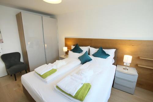 a bedroom with a large white bed with green pillows at Seehaus SeeZeit - Am Hafen in Neusiedl am See