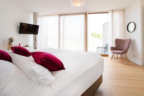 a white bed with red pillows in a bedroom at Seehaus SeeZeit - Am Hafen in Neusiedl am See