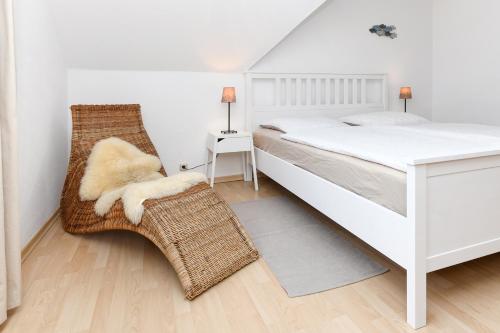 ein Schlafzimmer mit einem weißen Bett und einem Stuhl in der Unterkunft Ferienwohnungen im Haus Lieblingskoje in Neuharlingersiel