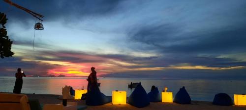 a man standing on the beach with a kite in the sunset at TropiCoco Beach Resort Koh Phangan in Haad Yao
