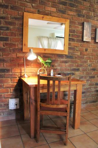 a wooden desk with a mirror and a plant on it at Ngwenya Boutique Hotel in Lephalale