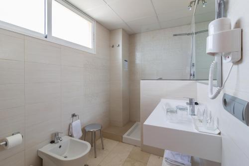 a white bathroom with a sink and a toilet at Hotel Porto Calpe in Calpe