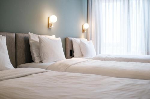 two beds in a hotel room with white pillows at Mercure Hotel Pforzheim in Pforzheim