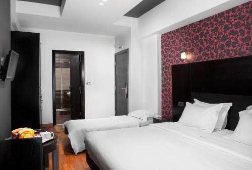 a bedroom with two beds and a red accent wall at Areos in Athens