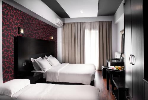 a hotel room with two beds and a red wall at Areos in Athens