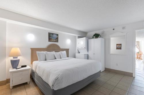 een slaapkamer met een wit bed en een witte koelkast bij Beachfront Condo w Balcony in Myrtle Beach in Myrtle Beach
