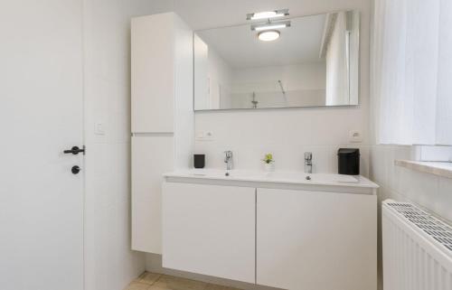 a white bathroom with a sink and a mirror at De Boei - Koksijde in Koksijde