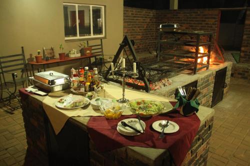 a table with plates of food on it with a fireplace at Ngwenya Boutique Hotel in Lephalale