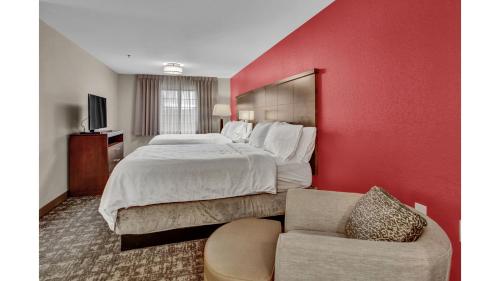a hotel room with a large bed and a chair at Staybridge Suites Salt Lake-West Valley City by IHG in West Valley City