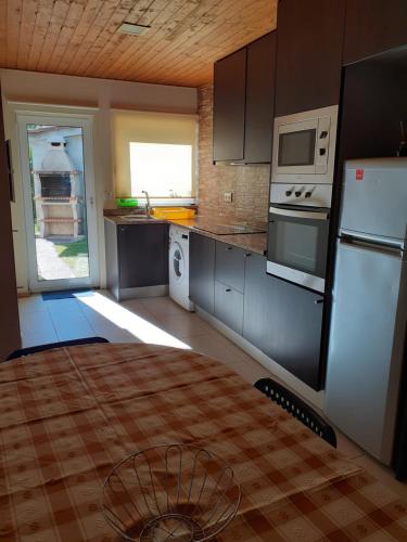 a kitchen with a white refrigerator and a microwave at Cantinho Cruzeiro in Vieira do Minho