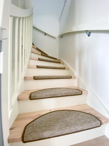 a staircase in a house with white walls and wooden stairs at New Åkrahamn coast house in Sæveland